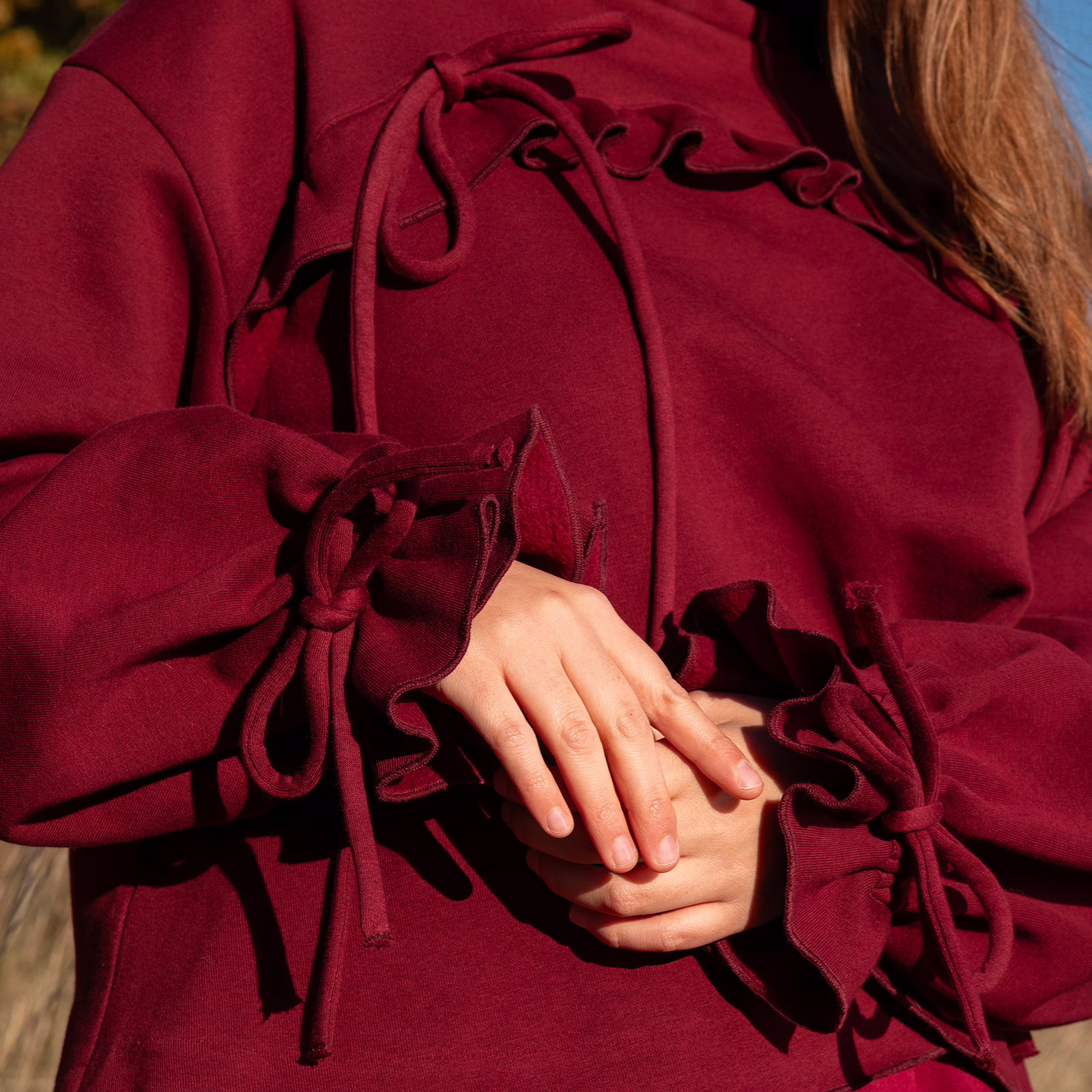 Mikina ASTER, vínová barva, detail vázání rukávu a volánu, na modelce